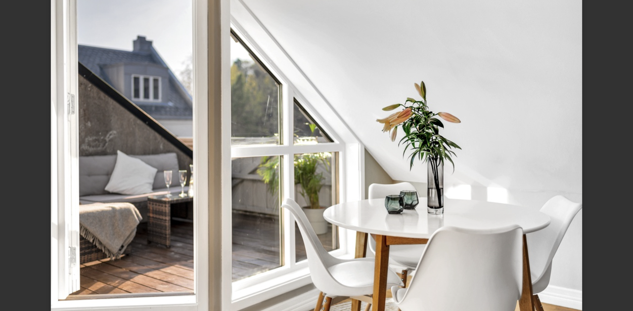 Et lyst spisehjørne under skråtaket har direkte utgang til en solrik takterrasse med loungemøbler.