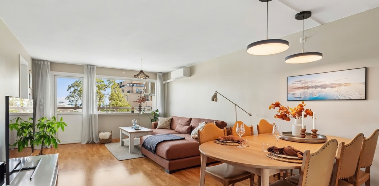 Store vindusflater slipper godt med dagslys inn i stuen, som har plass til både spisebord og sofaavdeling.