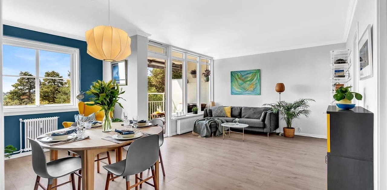 Den luftige stuen har plass til både spisebord og sofaavdeling, med store vindusflater og direkte utgang til balkongen.