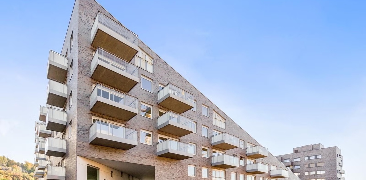Det moderne leilighetsbygget kjennetegnes av en stram teglsteinsfasade med utstikkende balkonger og en særpreget, skrånende arkitektur.