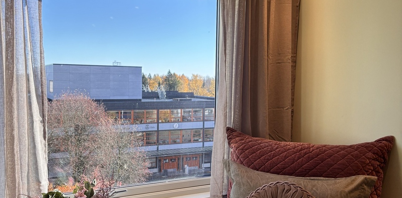 Soverommet har en seng plassert rett ved et stort vindu som slipper inn mye naturlig lys og byr på god utsikt.