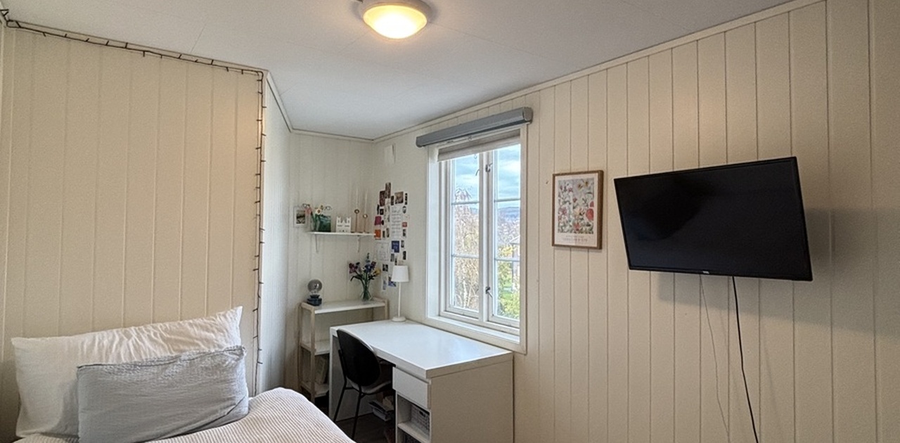 Soverom. Møblert med seng, pult, stol, tv, og klesskap.