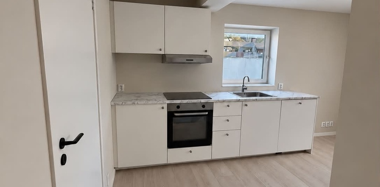 Kjøkkeninnredningen har slette, hvite fronter med integrert stekeovn, platetopp og oppvaskmaskin. Frittstående kombiskap.